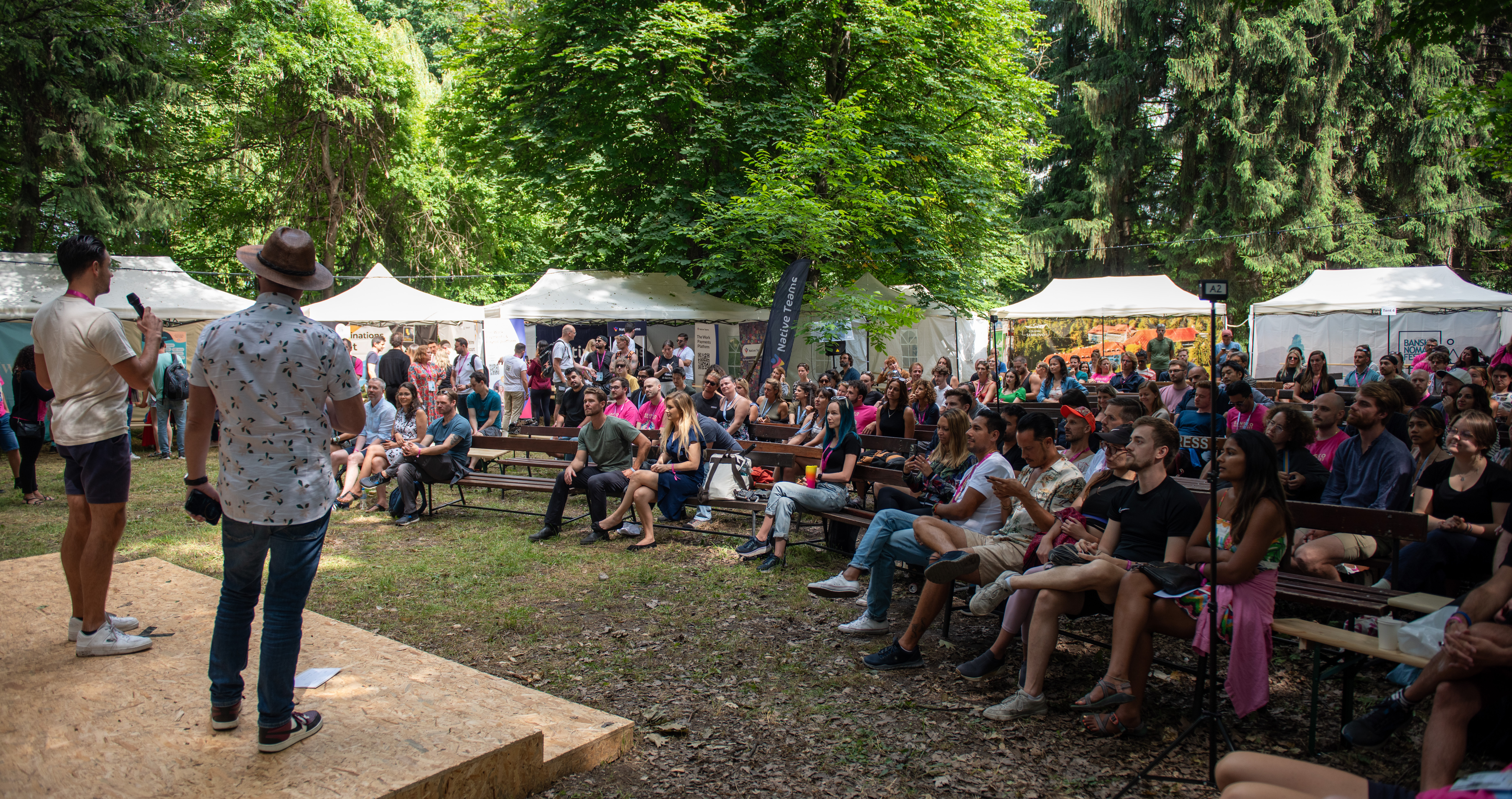A packed outdoor crowd at Bansko Nomad Fest's unconference, watching a pitching session under the trees