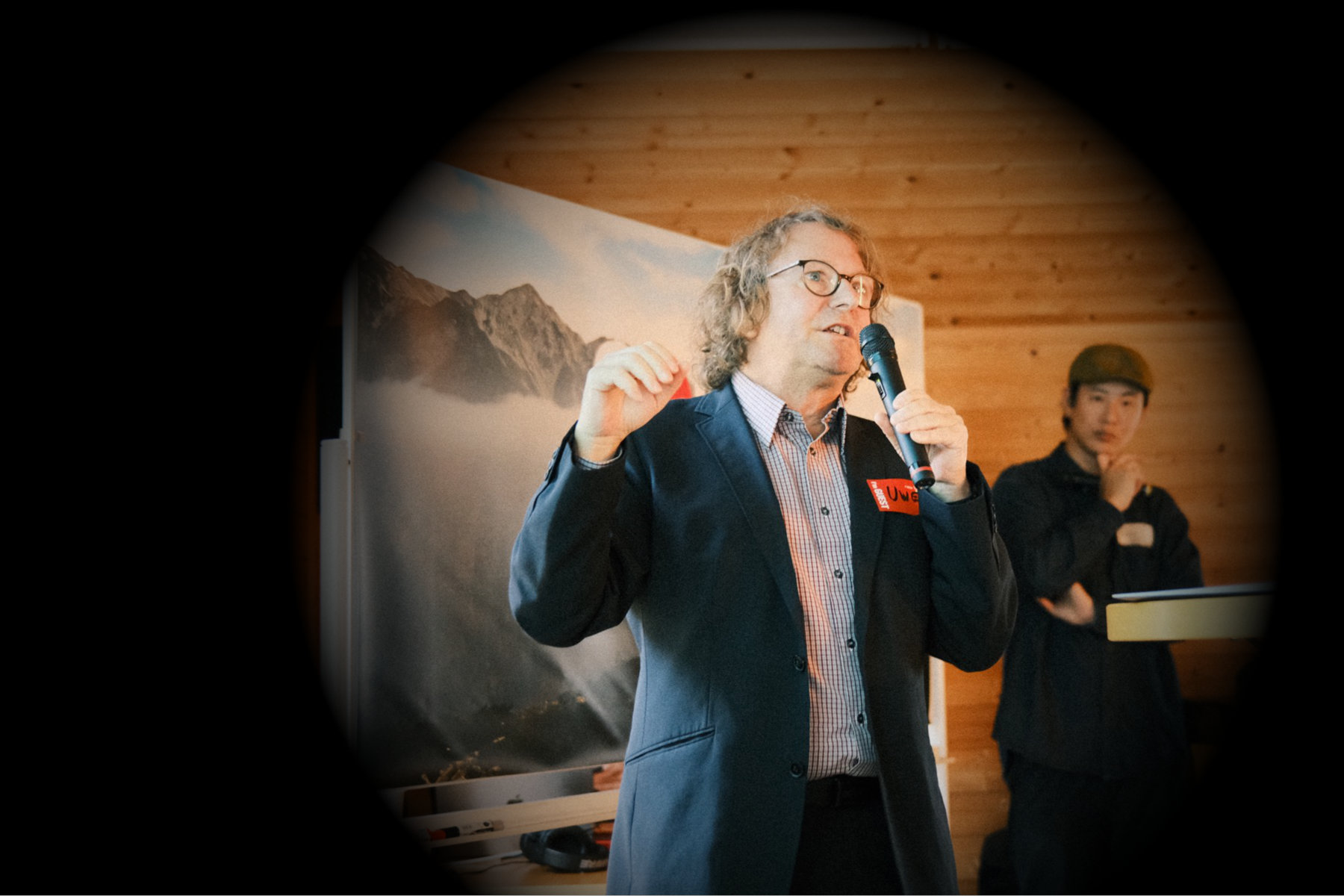 Uwe Allgäuer mid-talk with a microphone, speaking to a room about turning ski towns into nomad hubs